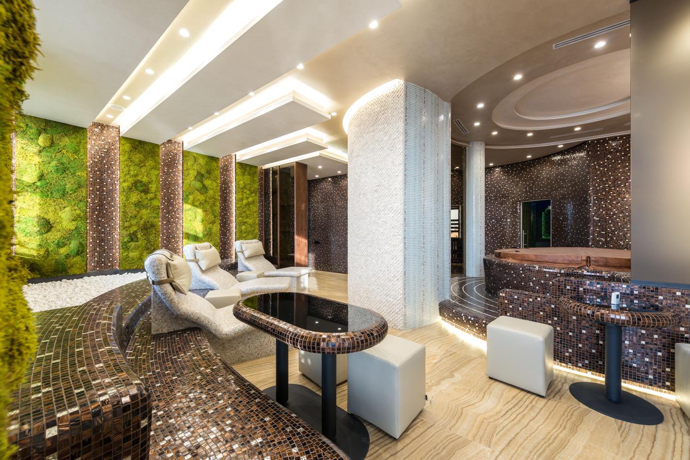 Modern spa lounge with tiled loungers, a living moss wall and a hot tub